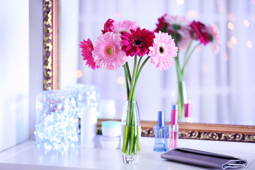 Bouquet of fresh gerbers in vase in front of the mirror indoors
