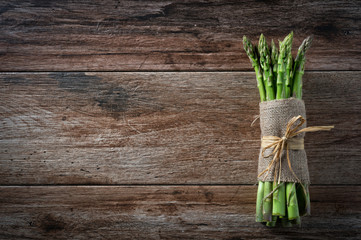 Bunch of fresh asparagus tied with a rope on wooden rustic background. Copy space.