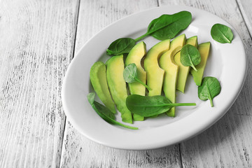 Slices of fresh avocado on wooden background