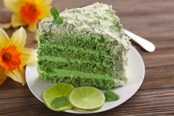 Piece of delicious creamy lime cake on wooden table closeup