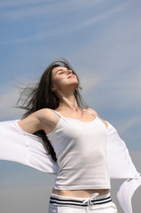 Girl breathes in fresh air on a blue sky background.