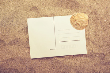 Fototapeta na wymiar Blank postcard and sea shell in hot beach sand
