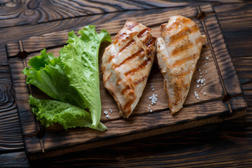 Grilled chicken breast and green salad, rustic wooden setting