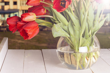 spring flowers, bouquet of red tulips on a window with a view of the city skyline.  happy family and cozy home. Copy space for text.