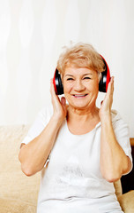 Naklejka premium Happy senior woman wearing red headphones 