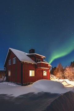 Illuminated house with aurora borealis in background