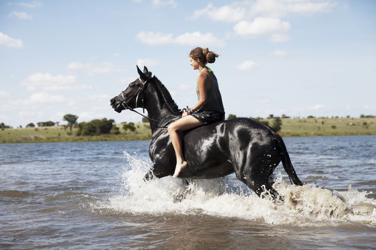 Woman riding horse across river