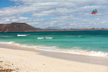  Unknown kitesurfer surfing on a flat azure water of Atlantic ocean in Corralejo, Fuerteventura, Canary islands, Spain