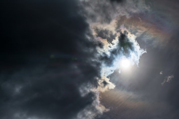 the sun peeking out from behind the dark rain clouds
