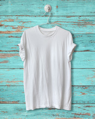 White t-shirt hang on blue wood vintage background.