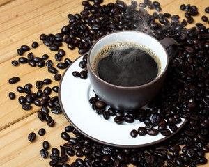 Coffee cup and coffee beans on a wood background.