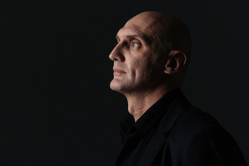Fototapeta premium Profile of attractive boldheaded businessman in dark suit