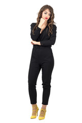 Pensive woman with head resting on her hand looking down. Full body length portrait isolated over white studio background.