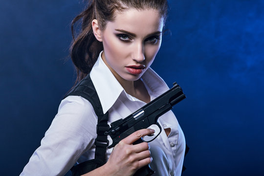 beautiful sexy girl holding gun . smoke background