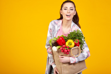 woman with green vegan food. Shopping bag. surprise emotion. Yel