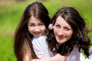 Daughter with the mother sitting on the grass and talking