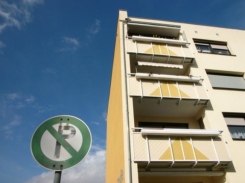 Parken verboten auf einem Privatparkplatz vor einem Mietshaus mit Fassade in Beige und Naturfarben vor blauem Himmel im Sonnenschein in Großauheim am Main bei Hanau im Main-Kinzig-Kreis in Hessen