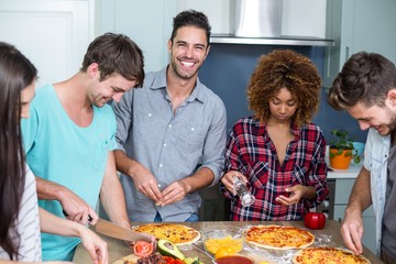 Obraz na płótnie Canvas Cheerful young friends preparing pizza at home