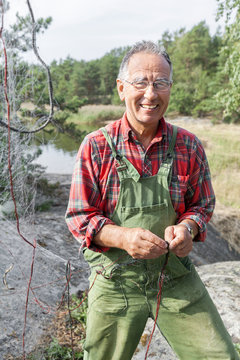 Smiling senior man repairing fishing net