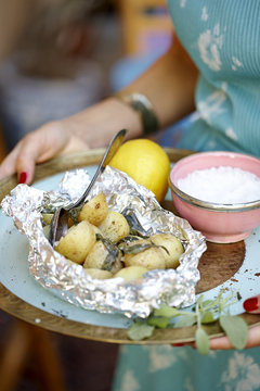 Woman carrying tray with baked potatoes