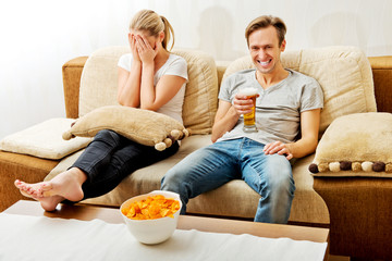 Woman sitting bored while man watching sports