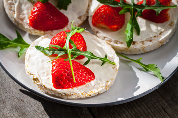 Multigrain rice cakes with strawberries fruit , soft mascarpone cheese and arugula for healthy breakfast.
