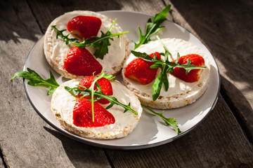 Multigrain rice cakes with strawberries fruit , soft mascarpone cheese and arugula for healthy breakfast.