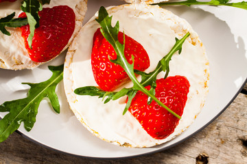 Multigrain rice cakes with strawberries fruit , soft mascarpone cheese and arugula for healthy breakfast.