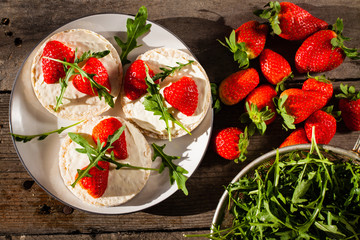 Multigrain rice cakes with strawberries fruit , soft mascarpone cheese and arugula for healthy breakfast.
