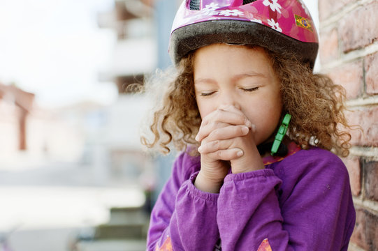 Girl wearing safety helmet, praying