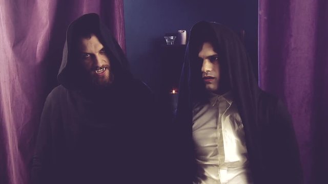 Two angry cool handsome male vampires posing showing fangs looking camera