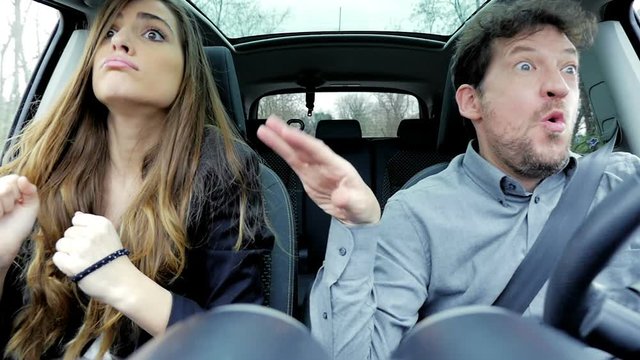 Beautiful business woman with man making funny crazy faces in car slow motion