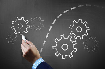 Man drawing gears on blackboard