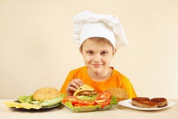 Little funny chef puts cheese on the hamburger