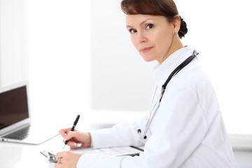 Woman doctor filling up medical history at the desk