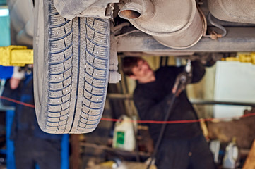 Car repairing in workshop. Mechanics are repairing a front car suspension.