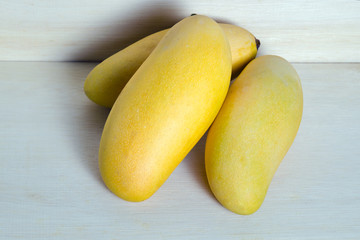 Ripe yellow mango on wooden background