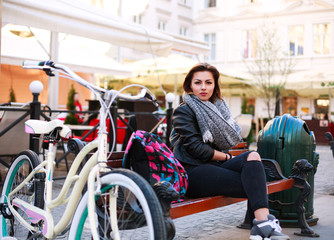Fototapeta na wymiar Girl with vintage bicycle sits in the street old town