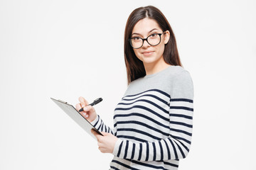 Happy woman writing notes in clipboard