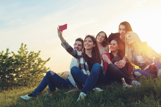Group of young people taking a selfie outdoors, having fun