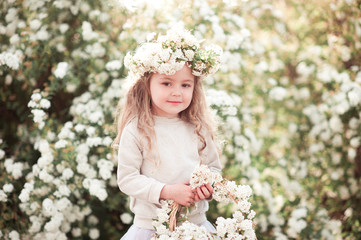 Cute kid girl 3-4 year old wearing stylish clothes and holding basket with flowers outdoors. Childhood. Looking at camera. 