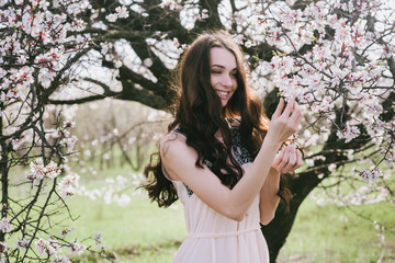 Beautiful brunette woman in the park standing near the blossom tree on a warm summer day,lifestyle