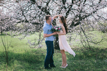 Young couple in love outdoor.Stunning sensual outdoor portrait of young stylish fashion couple posing in spring near blossom tree