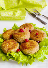Roasted chicken cutlets on green lettuce on white table.