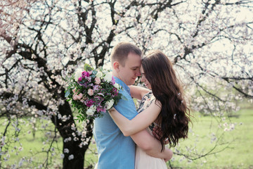 Young couple in love outdoor.Stunning sensual outdoor portrait of young stylish fashion couple posing in spring near blossom tree