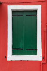 Obraz na płótnie Canvas Old window with dark green shutters on red wall