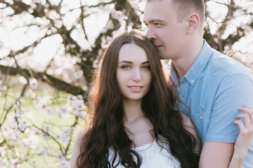Young couple in love outdoor.Stunning sensual outdoor portrait of young stylish fashion couple posing in spring near blossom tree