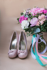 Beautiful wedding shoes with high heels and a bouquet of colorful flowers hydrangea, peonies and roses on a background of kraft paper, decorations, preparing for the wedding, details, boudoir