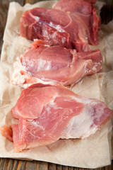 Raw pork chop steak on wooden cutting board.