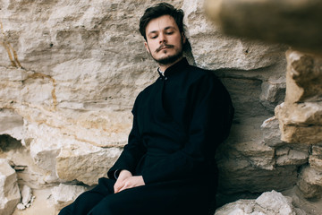 Portrait of handsome catholic bearded man priest or pastor posing outdoors in mountains